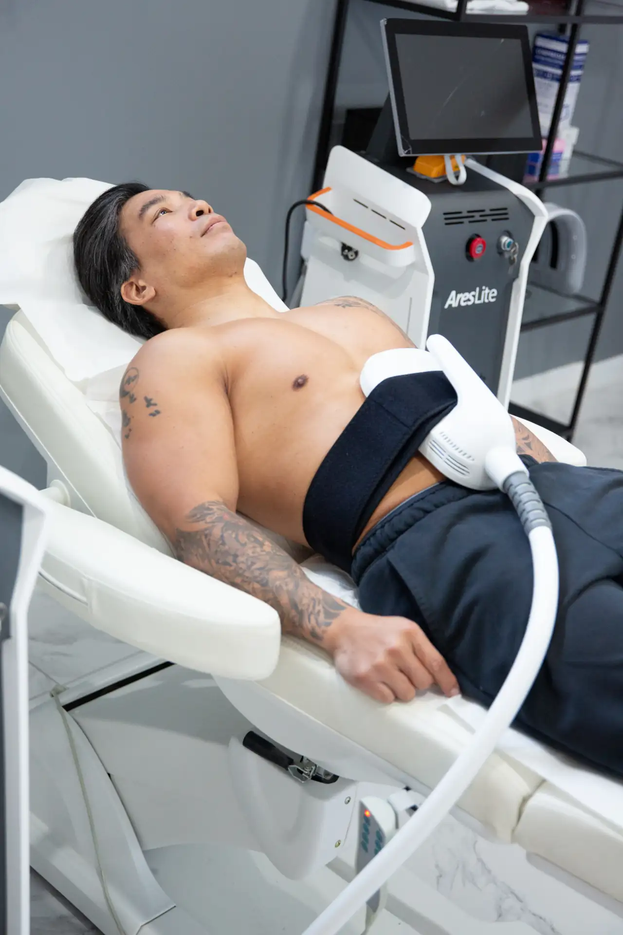 une image montrant un client allongé en train de pratiqué une sceance d'electrostimulation dans la clinique niptuck